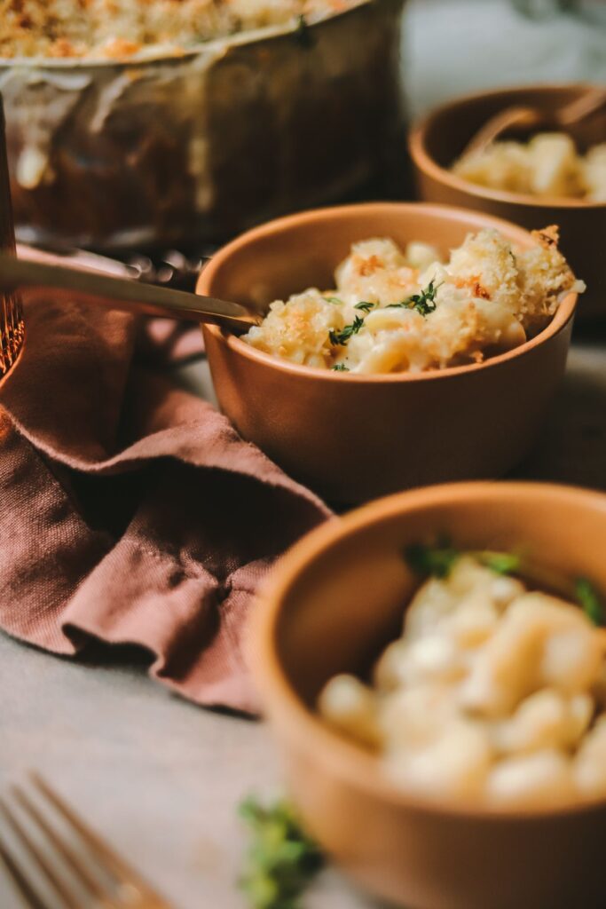 A bowl of brie mac and cheese with napkin and larger dish filled with it. 