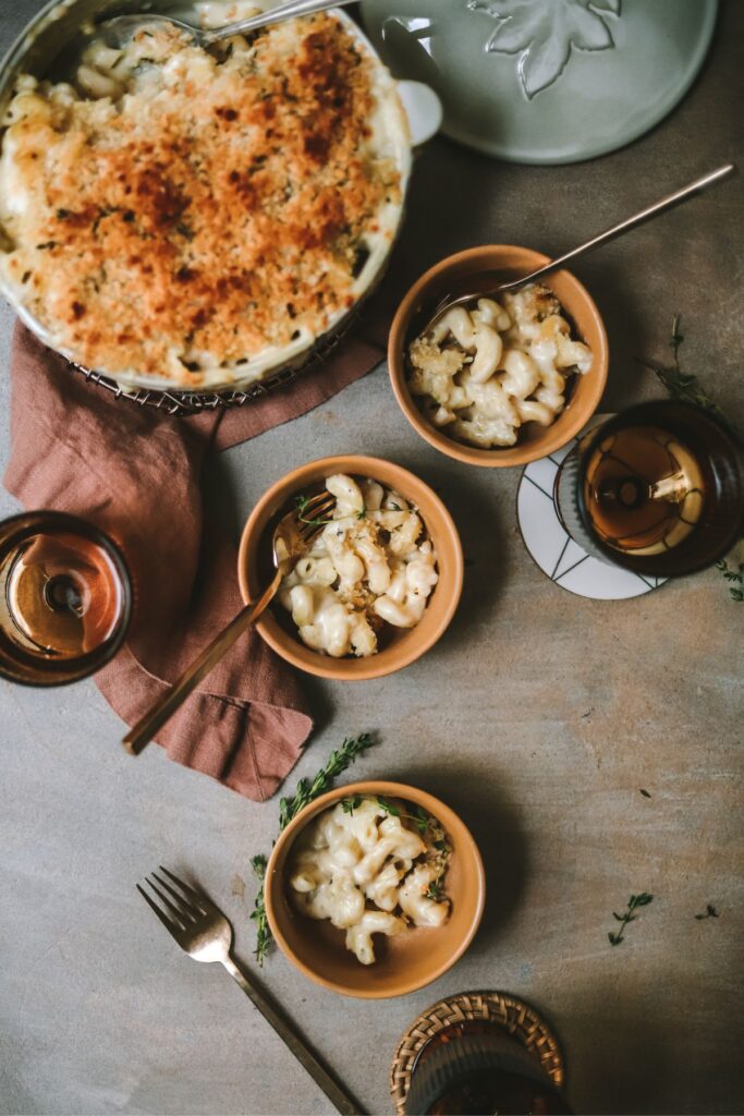 Three bowls of baked brie mac and cheese beside a larger bowl. 