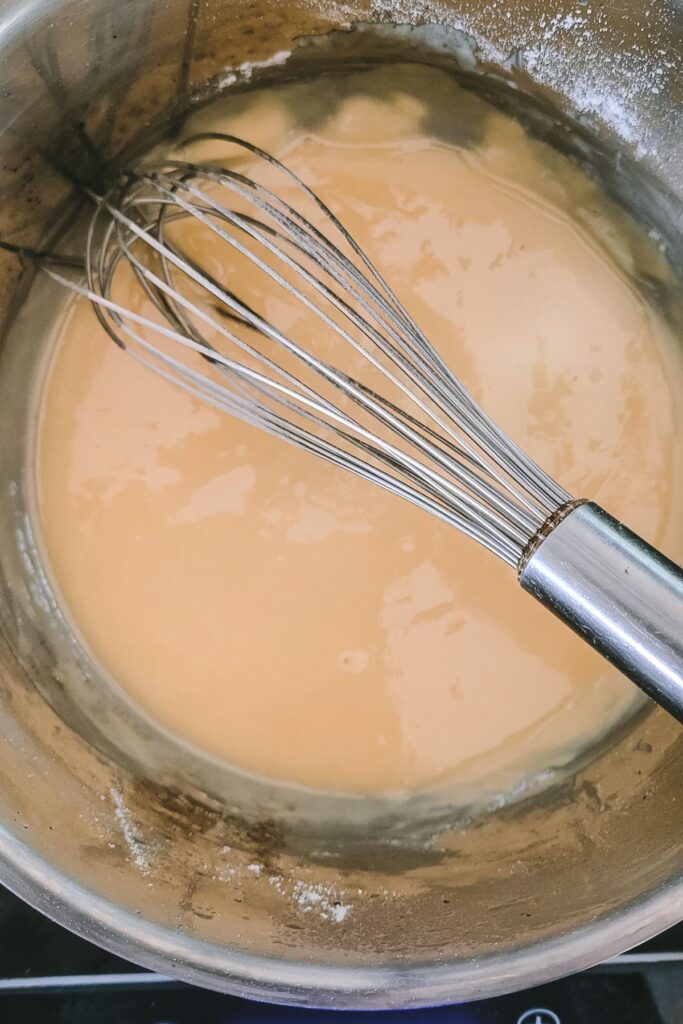 A roux in a pot with a whisk. 