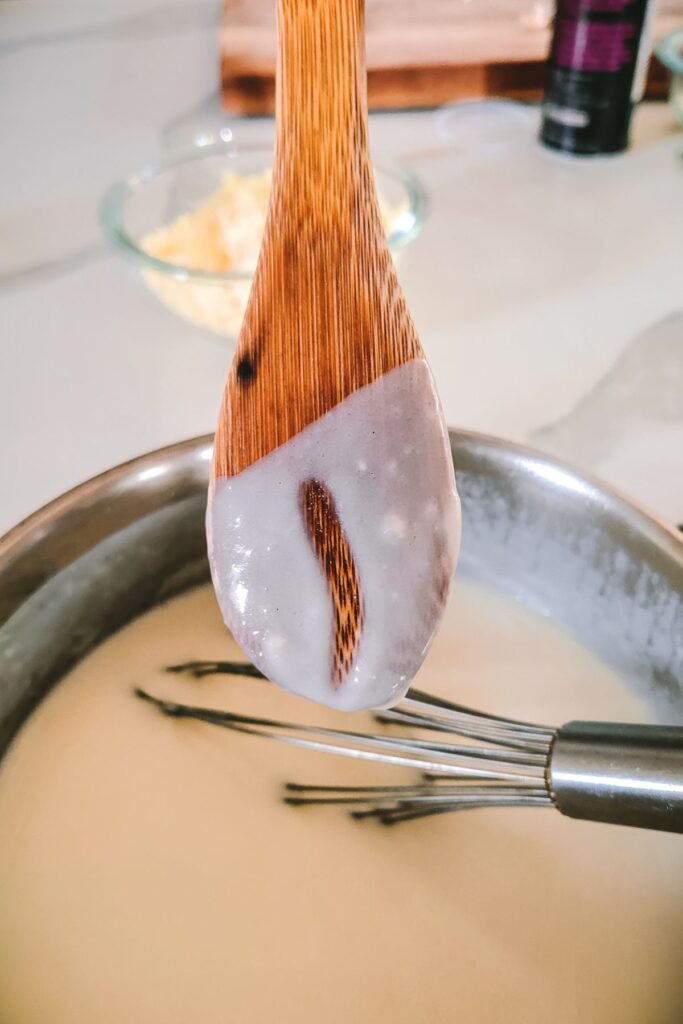A wooden spoon covered with sauce, a finger swipe down the middle. 