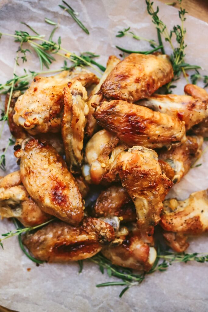Baked chicken wings on a platter with rosemary and thyme. 