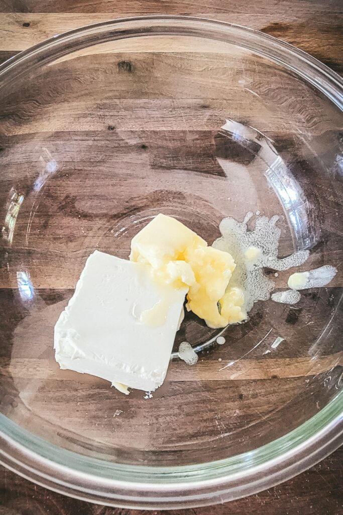 Adding butter and cream cheese to a glass bowl.