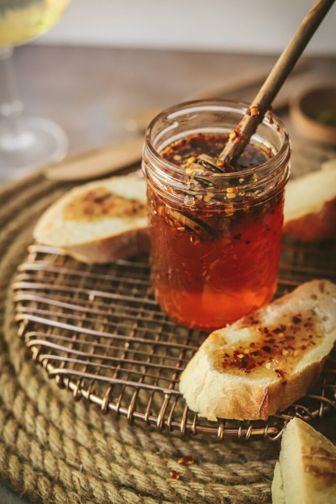 A jar of hot honey surrounded by bread.