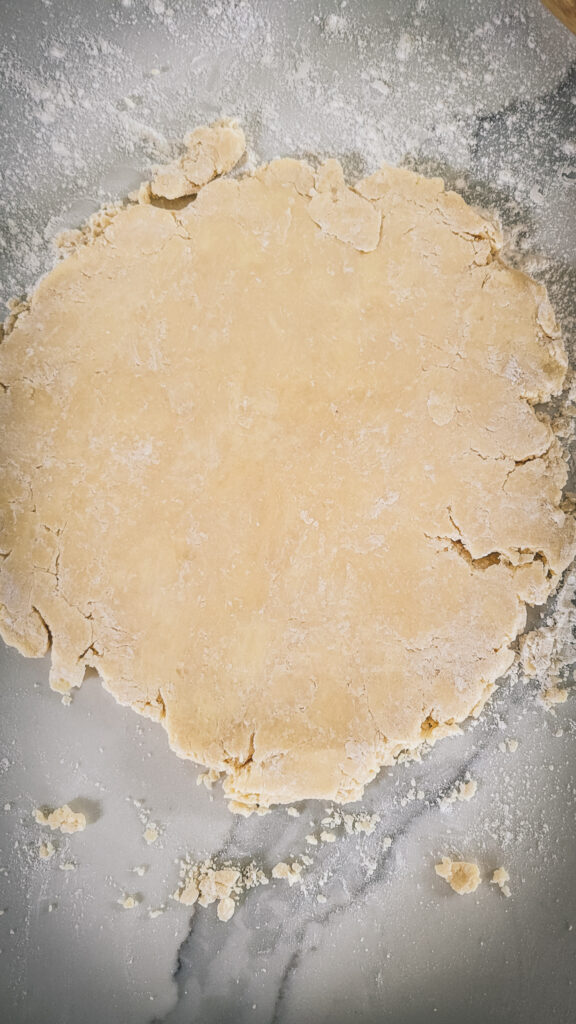 A pie crust partially rolled out