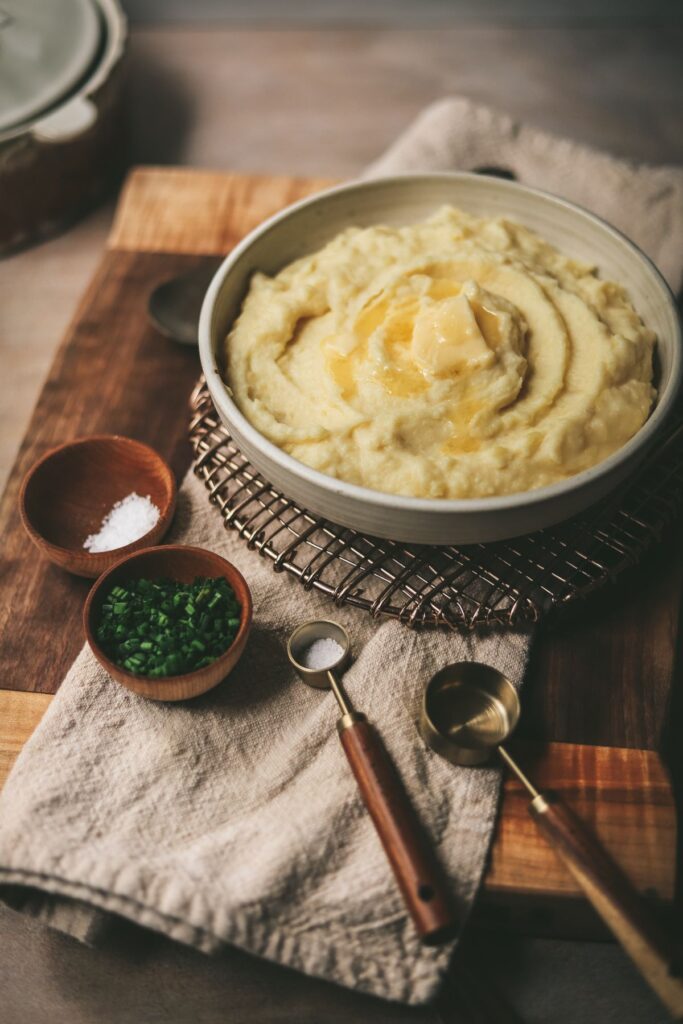 A bowl of creamy truffle mashed potatoes on a cutting board.