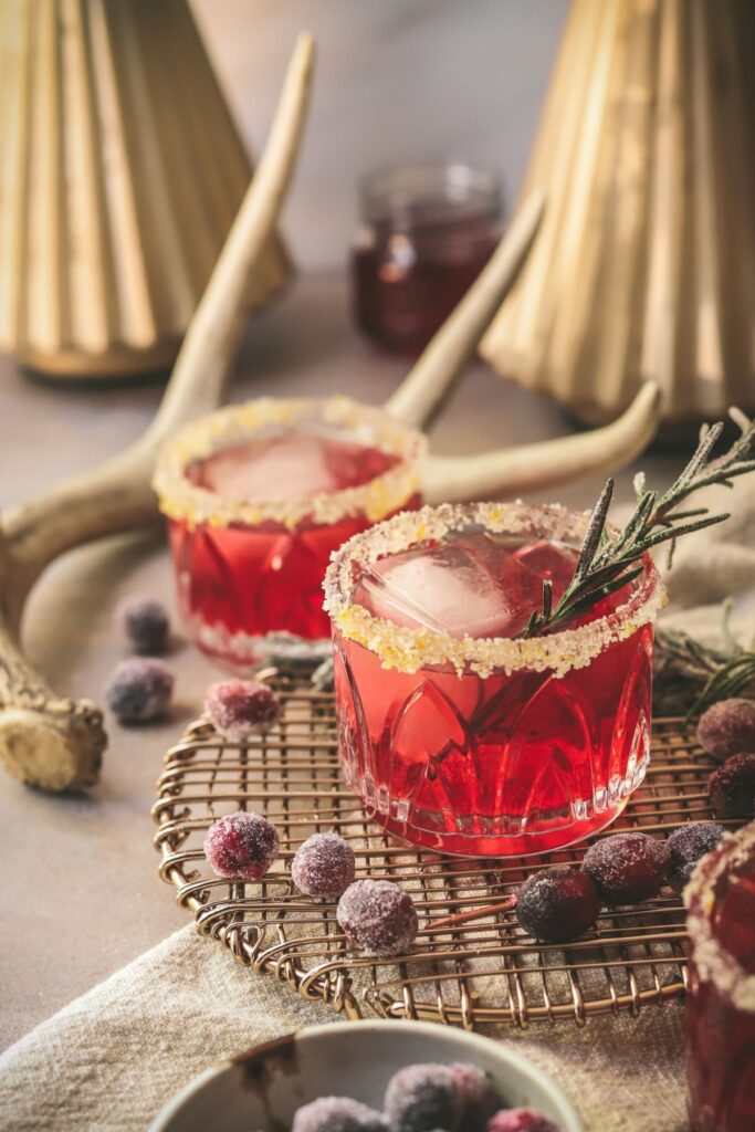 Two cranberry margaritas with sugared cranberry and rosemary.