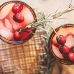 Three cranberry moscow mules with fresh cranberries and rosemary.