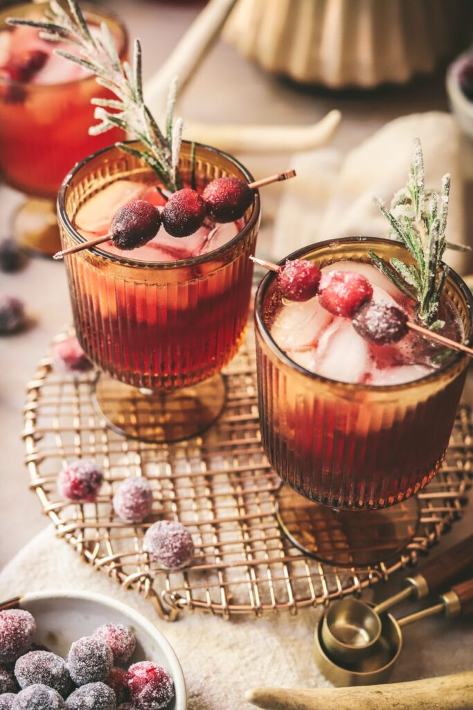 Two cranberry Moscow Mules with sugared cranberries and rosemary garnish. 