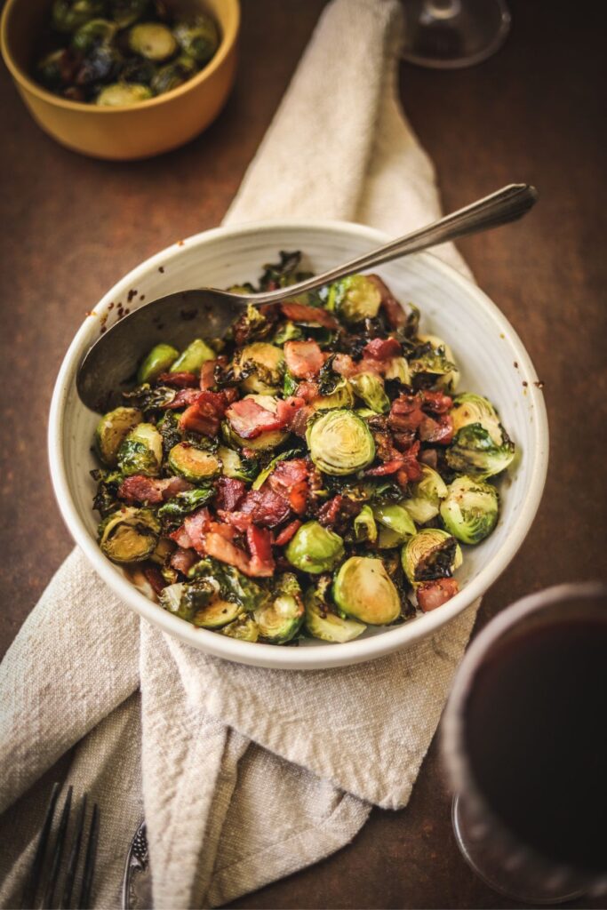 A bowl of brussel's sprouts with bacon and a spoon.