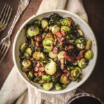 A bowl of brussels sprouts with bacon on a linen napkin.