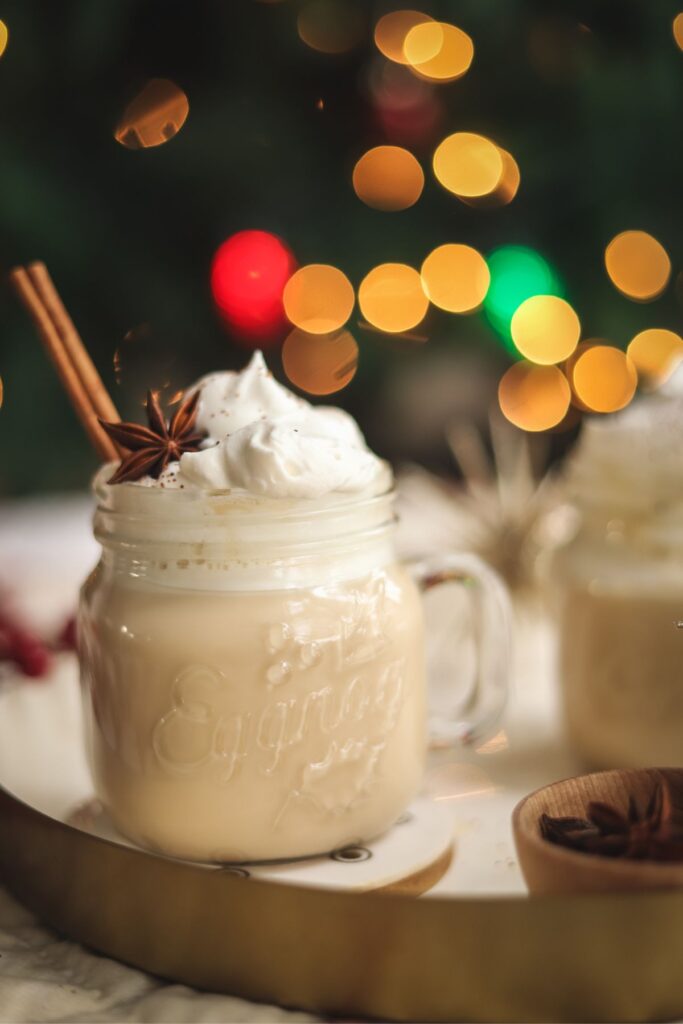 An eggnog latte in front of a Christmas tree. 