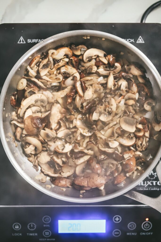 Mushrooms cooking in a large saucepan.
