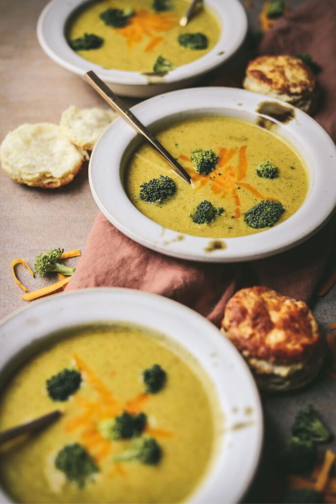 Instant pot broccoli cheddar soup, with a bowl on a napkin, and gold spoons.