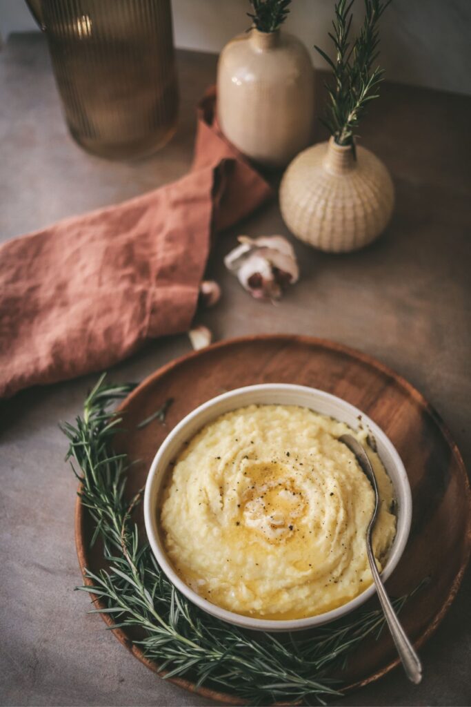 A bowl of mashed potatoes with butter and rosemary. 