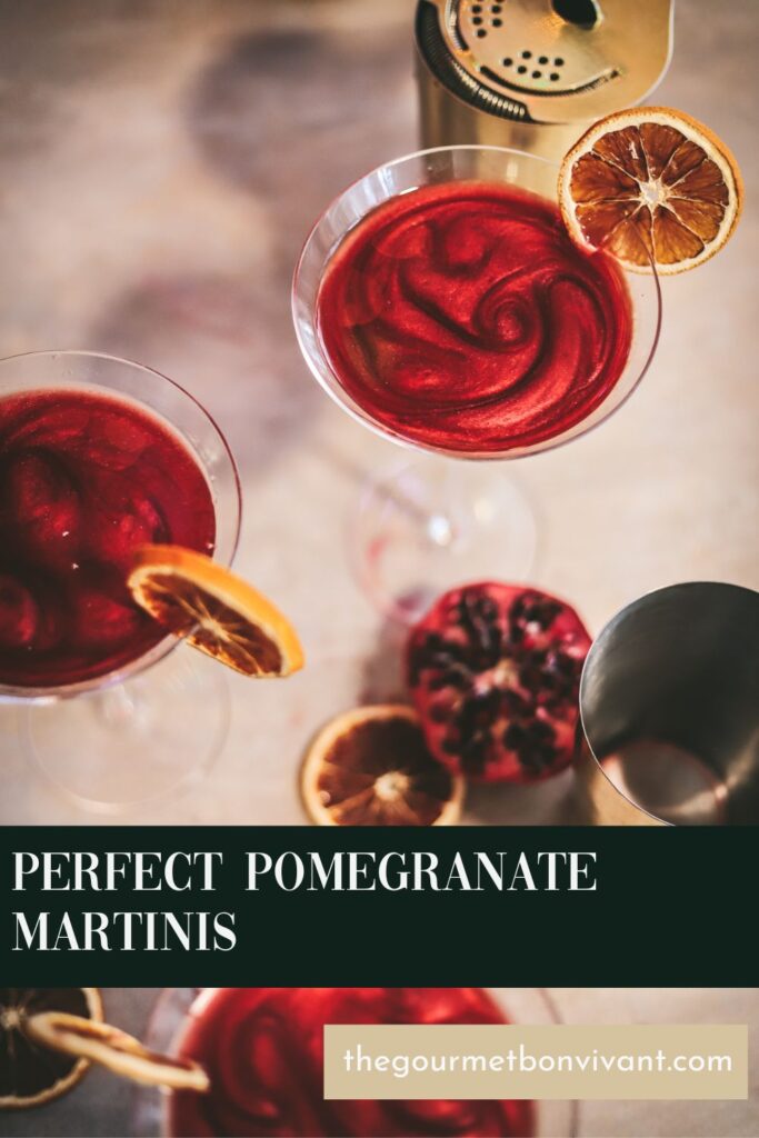 Pomegranate martinis surrounded by garnish and barware.