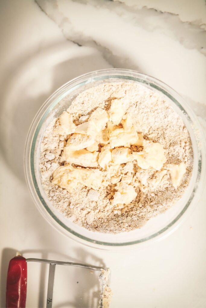 Adding the butter to the sugar, flour and oats. 