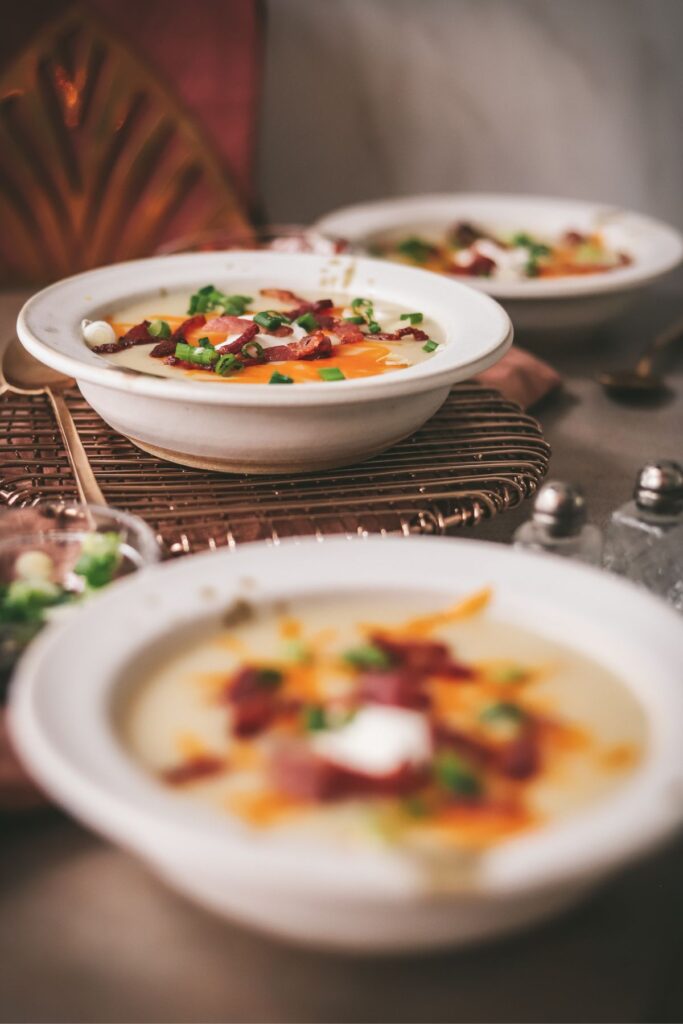 Potato soup bowls with toppings of bacon, onion, and sour cream. 