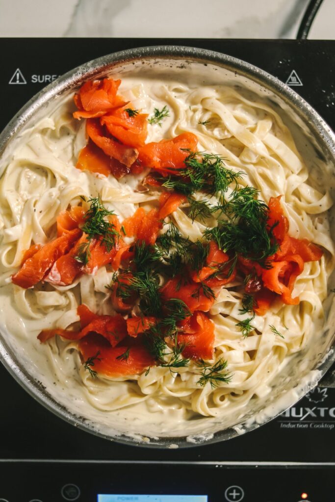 smoked salmon and herbs in the pan with the pasta and sauce. 