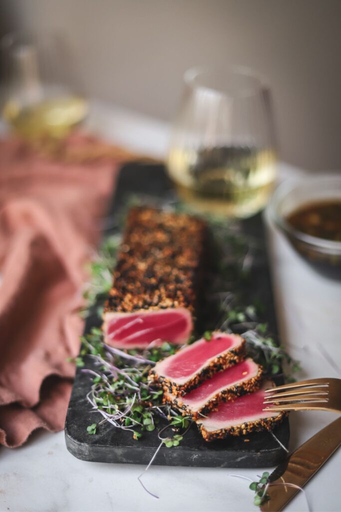 Tuna, sliced, cooked rare on a stone cutting board. 