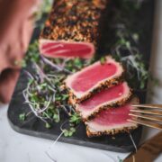 seared ahi tuna, sliced, with a fork and microgreens.