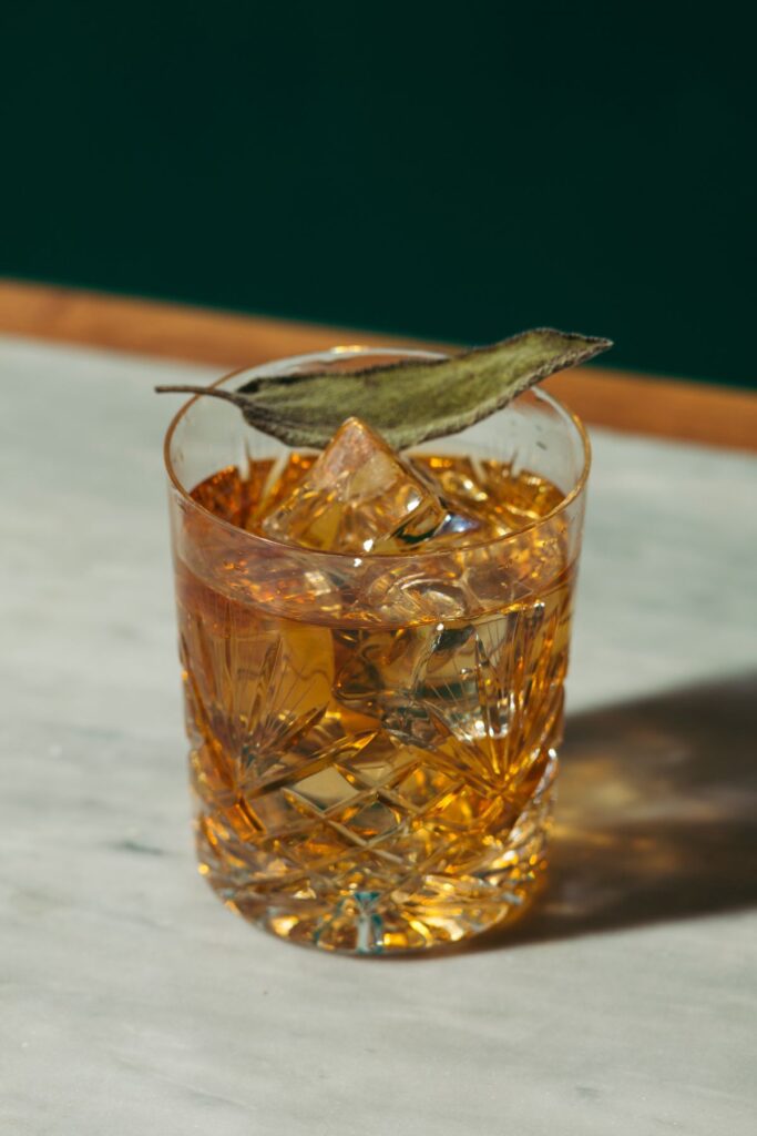 A glass of Amaro Nonino with ice and a sage leaf. 