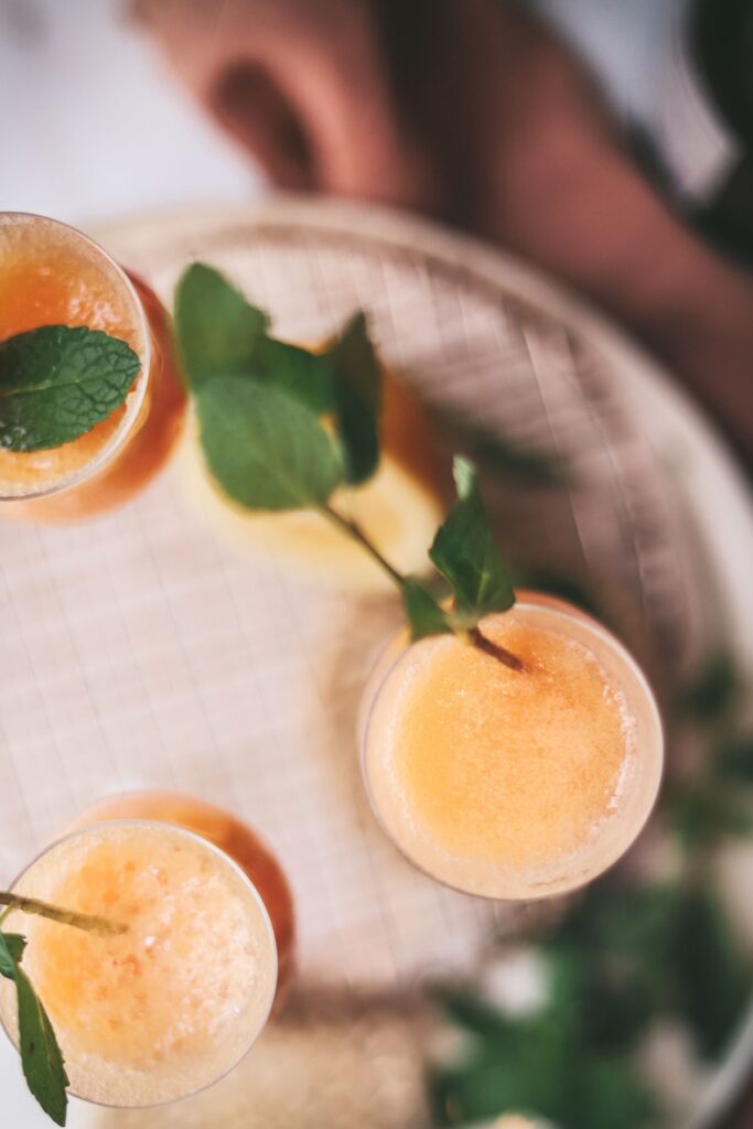 A bellini garnished with mint on top of a trivet. 