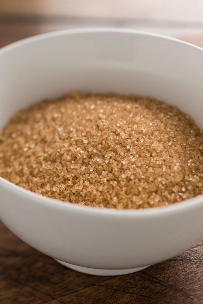 Demerara sugar in a white bowl on a wooden table. 