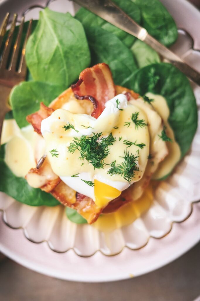 Eggs benedict with bacon, hollandaise, dill and spinach. 