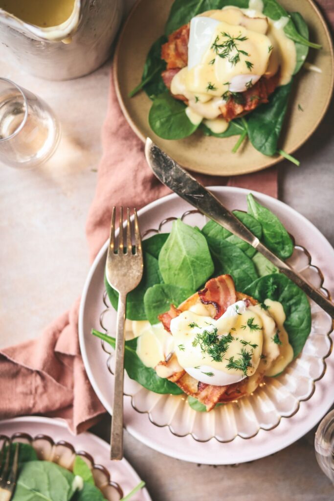 Three plates of eggs benedict with spinach. 
