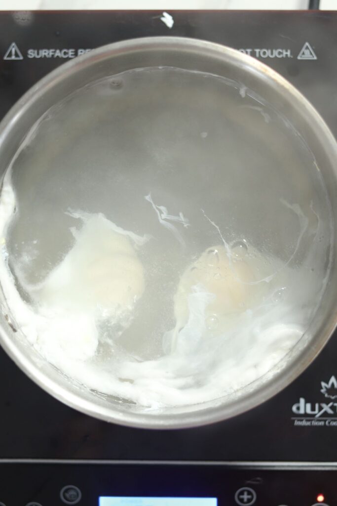 Eggs poaching in a saucepan. 