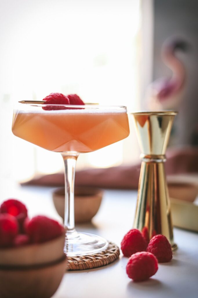A french martini with fresh raspberries and a gold jigger. 