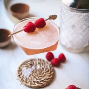 A French martini on a wicker coaster with fresh raspberries.