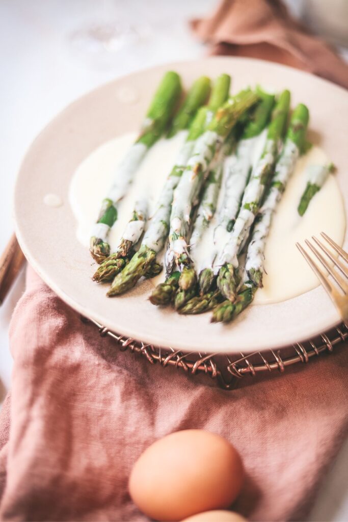 Asparagus on a pink napkin with mousseline sauce. 