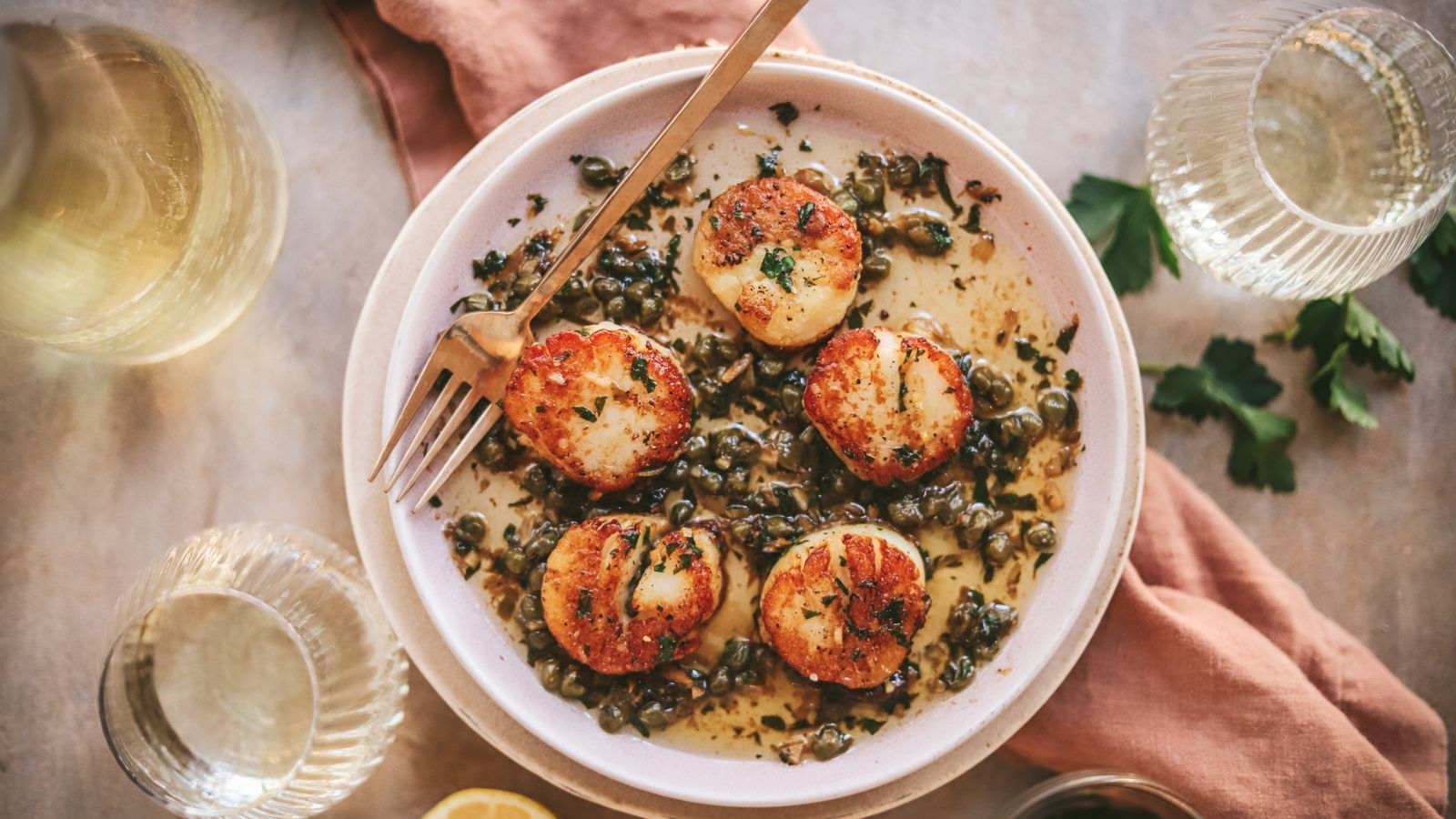 A plate of seared scallops with lemon butter an capers. 