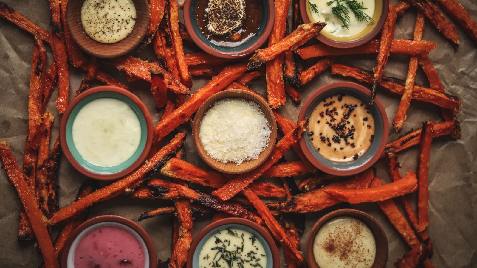 Dipping sauces surrounded by sweet potato fries. 
