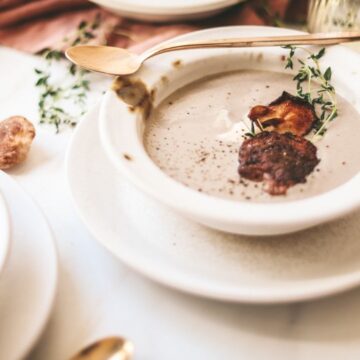 A bowl of cream of mushrooms soup with seared shiitakes and thyme.
