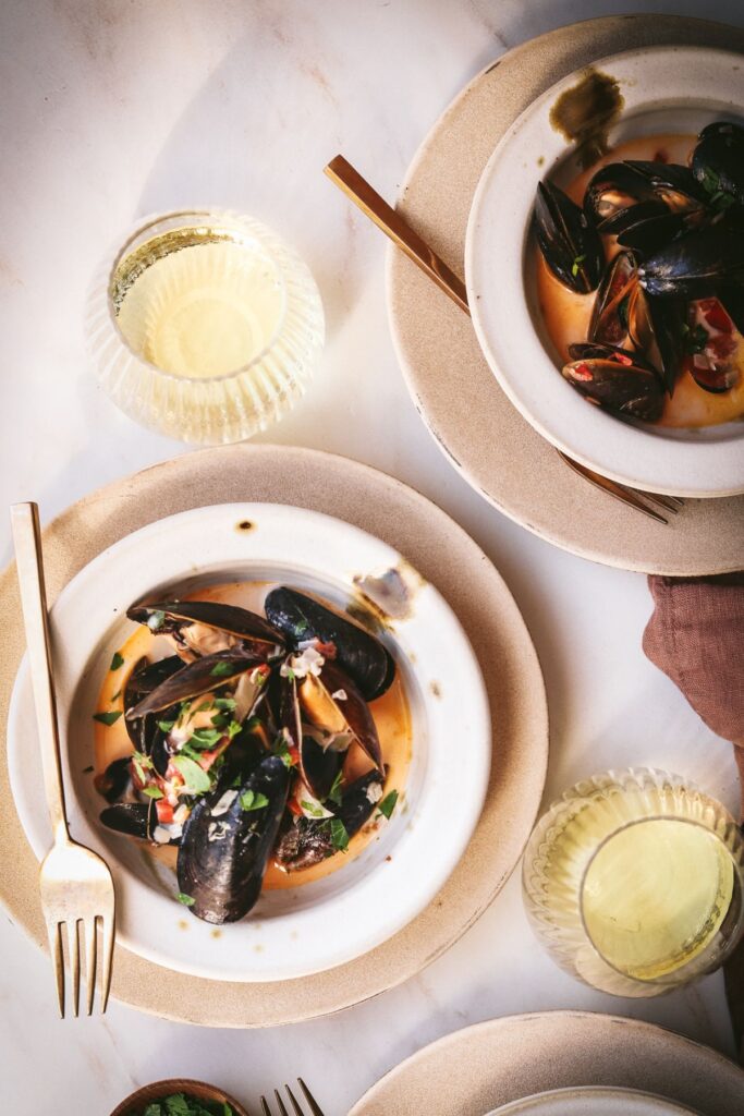 Bowls of mussels surrounded by white wine.