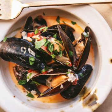 A bowl of mussels in white wine sauce.