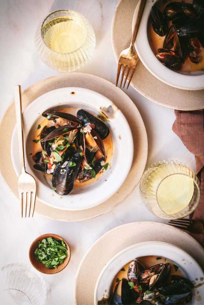 The bowls filled with a mussels recipe and gold cutlery. 