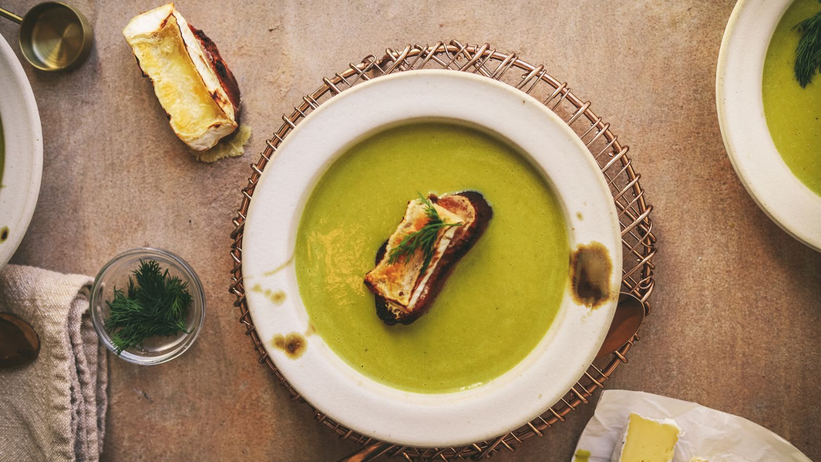 A bowl of asparagus soup with a brie crostini on the top. 