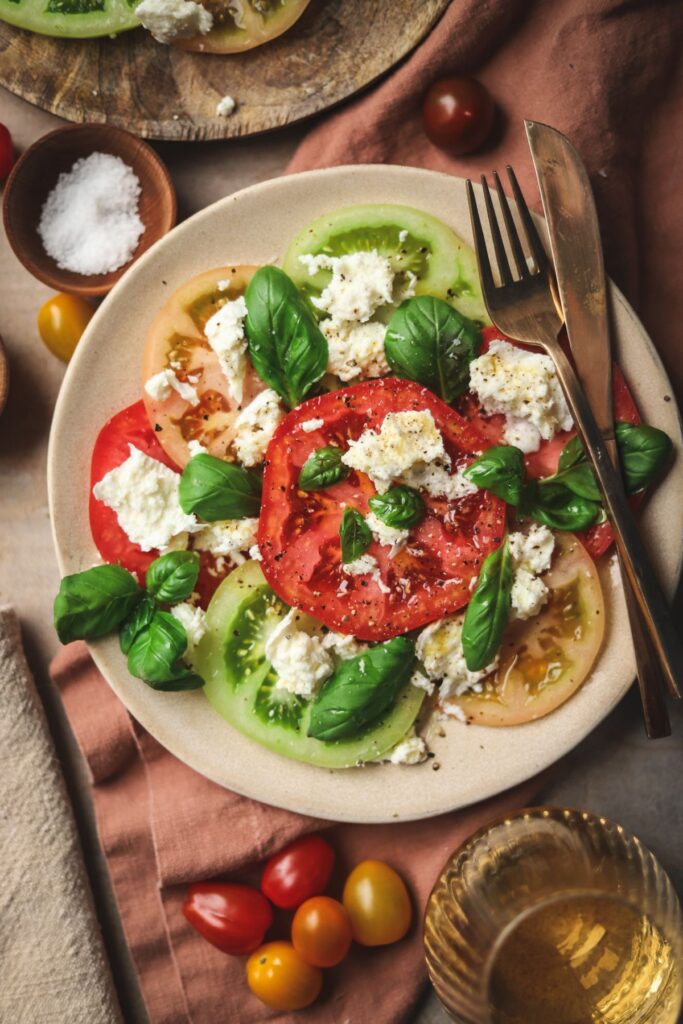 Two plates of simple tomato salad with fresh mozzarella and basil. 