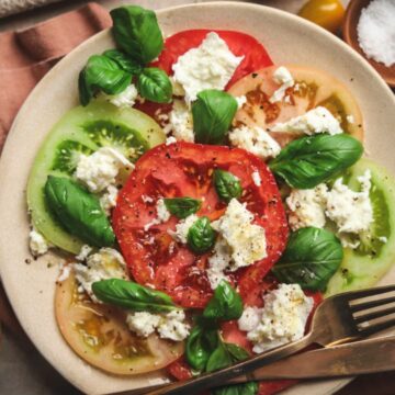 Caprese salad surrounded by cherry tomatoes and white wine.