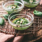Small bowls of pesto with pine nuts on top.