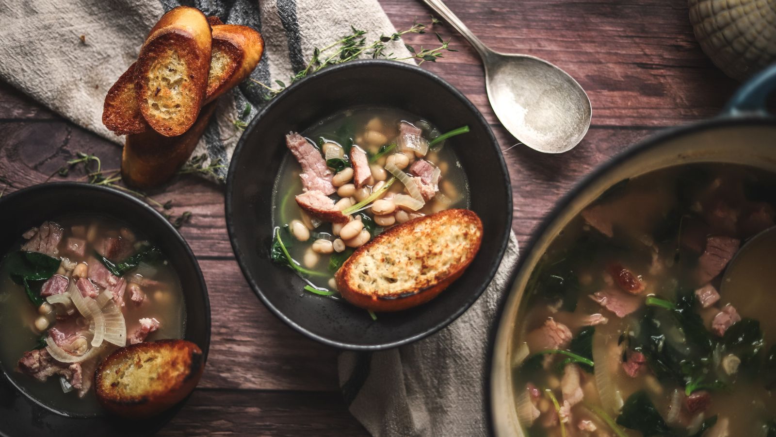 Two bowls of ham soup with golden crostini.