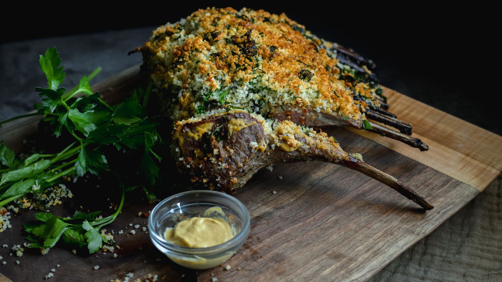 Panko and herb crusted rack of lamb on a wooden cutting board. 