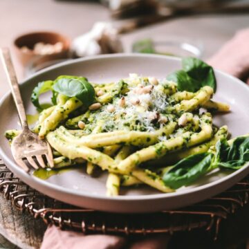 A plate of pesto pasta with fresh basil.