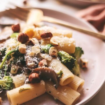A plate of creamy vegetable pasta with toasted hazelnuts.