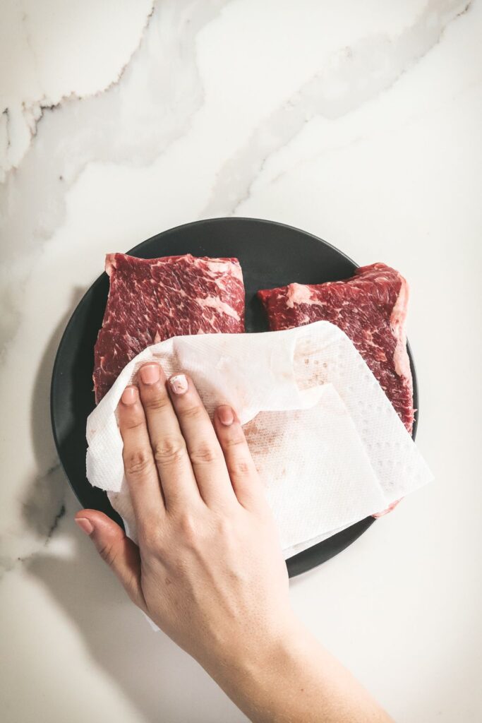 Patting the steak dry with a paper towel.
