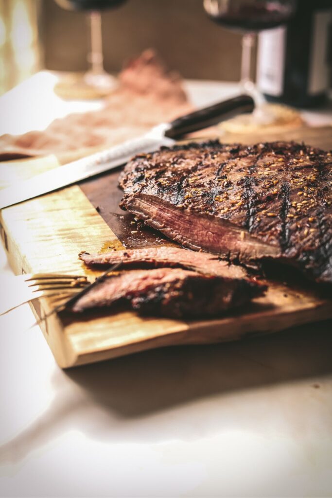 A flank steak on a wood cutting board, sliced. 