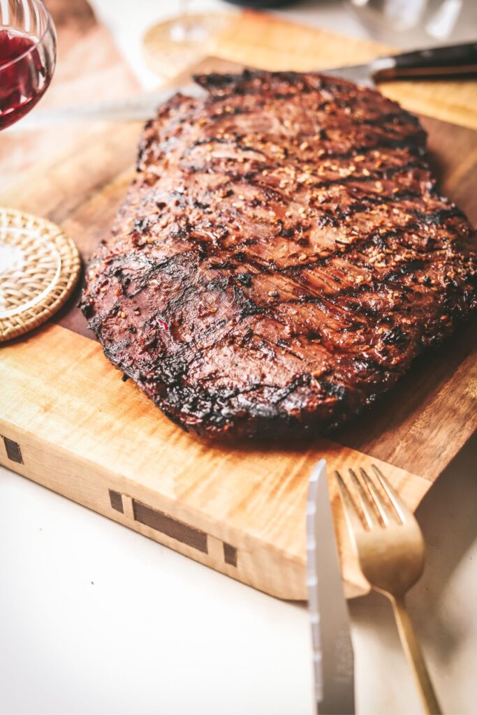 A whole flank steak on a wooden board. 